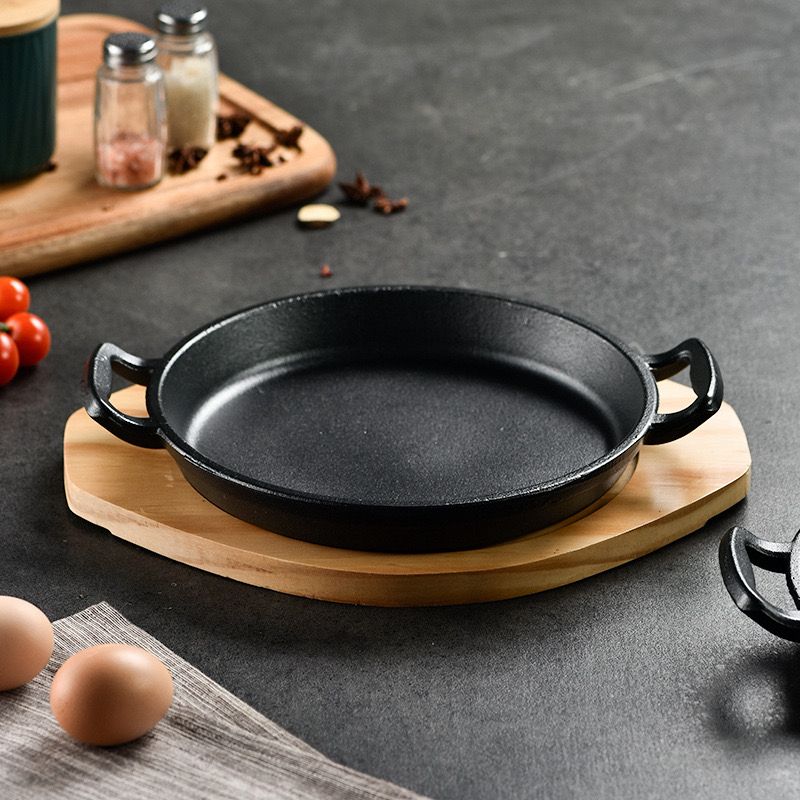 طاسة حديد زهر غير لاصق بيد وقاعدة خشبية لتسوية وتقديم الطعام علي السفرة وقت العزومات بشكل شيك